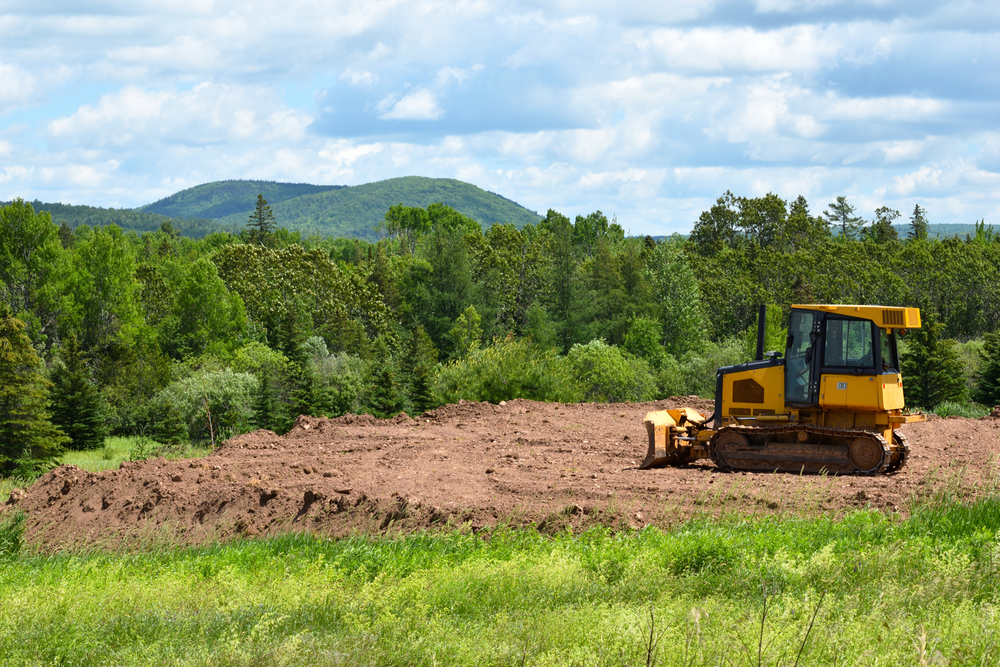 Yelllow,bulldozer,clearing,land,in,the,countryside,in,summer