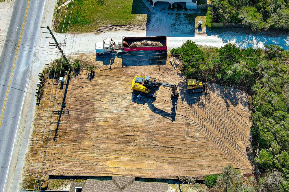 Aerial,perspective,of,a,yellow,excavator,preparing,a,vacant,lot.